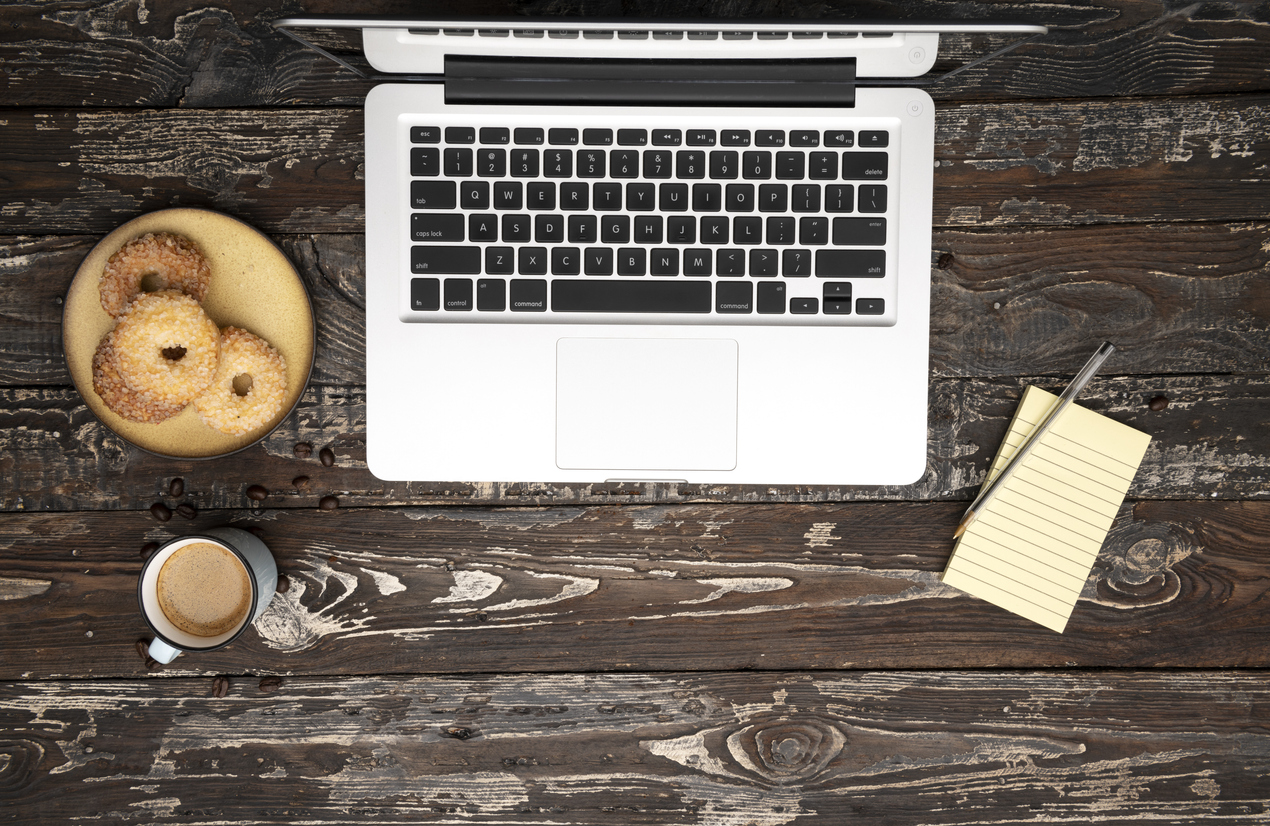 Laptop with office accessories on wooden table.